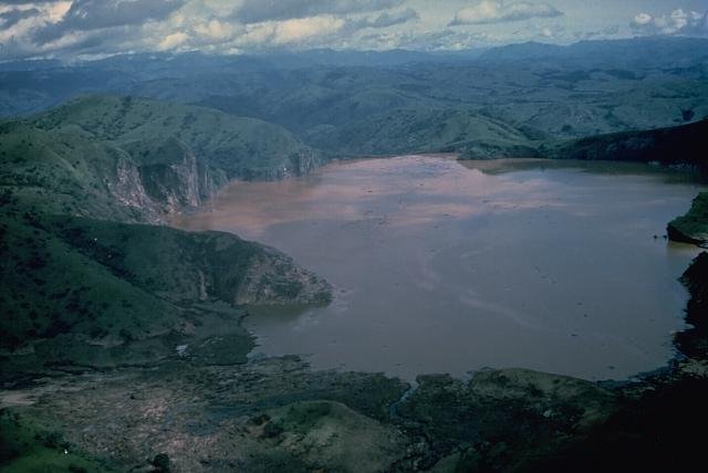 Crater lake in Cameroon surrounded by steep green hills.