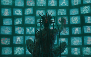 Person sitting alone with multiple screens glowing around them