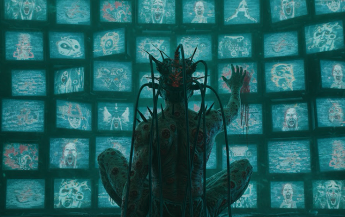 Person sitting alone with multiple screens glowing around them